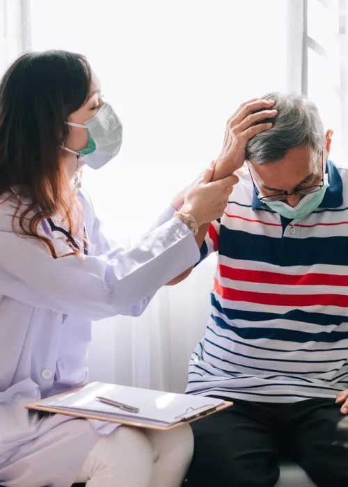 asian-doctor-visit-examines-senior-man-home-with-headage-pain-doctor-checking-up-consulting-retirement-health-hospital-services-wearing-mask-protect-covid19